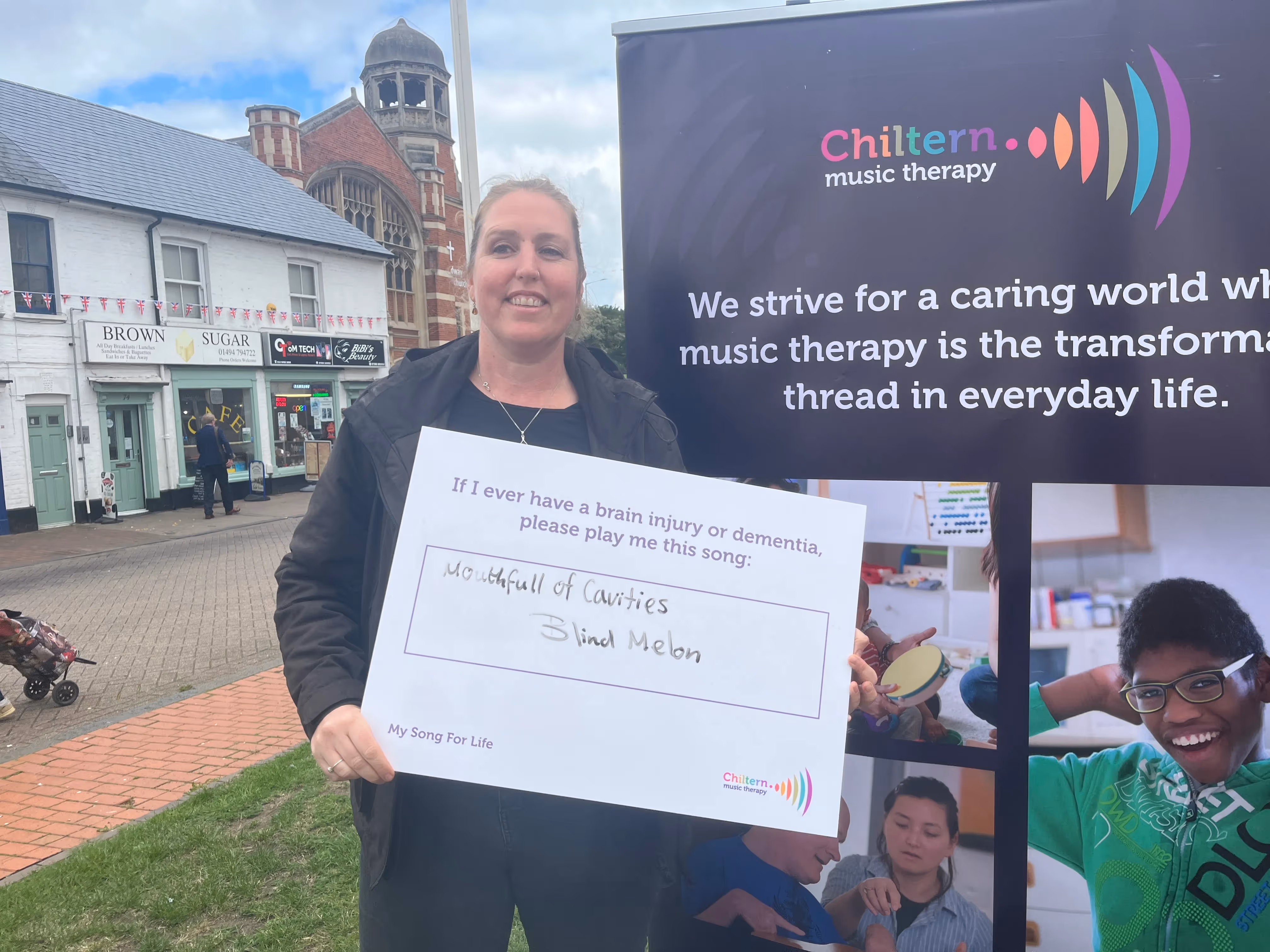 Image is of a women holding a sign that says "If I ever have a brain injury or dementia, please play me this song", underneath in handwriting it says "Mouthfull of Cavities - Blind Melon"