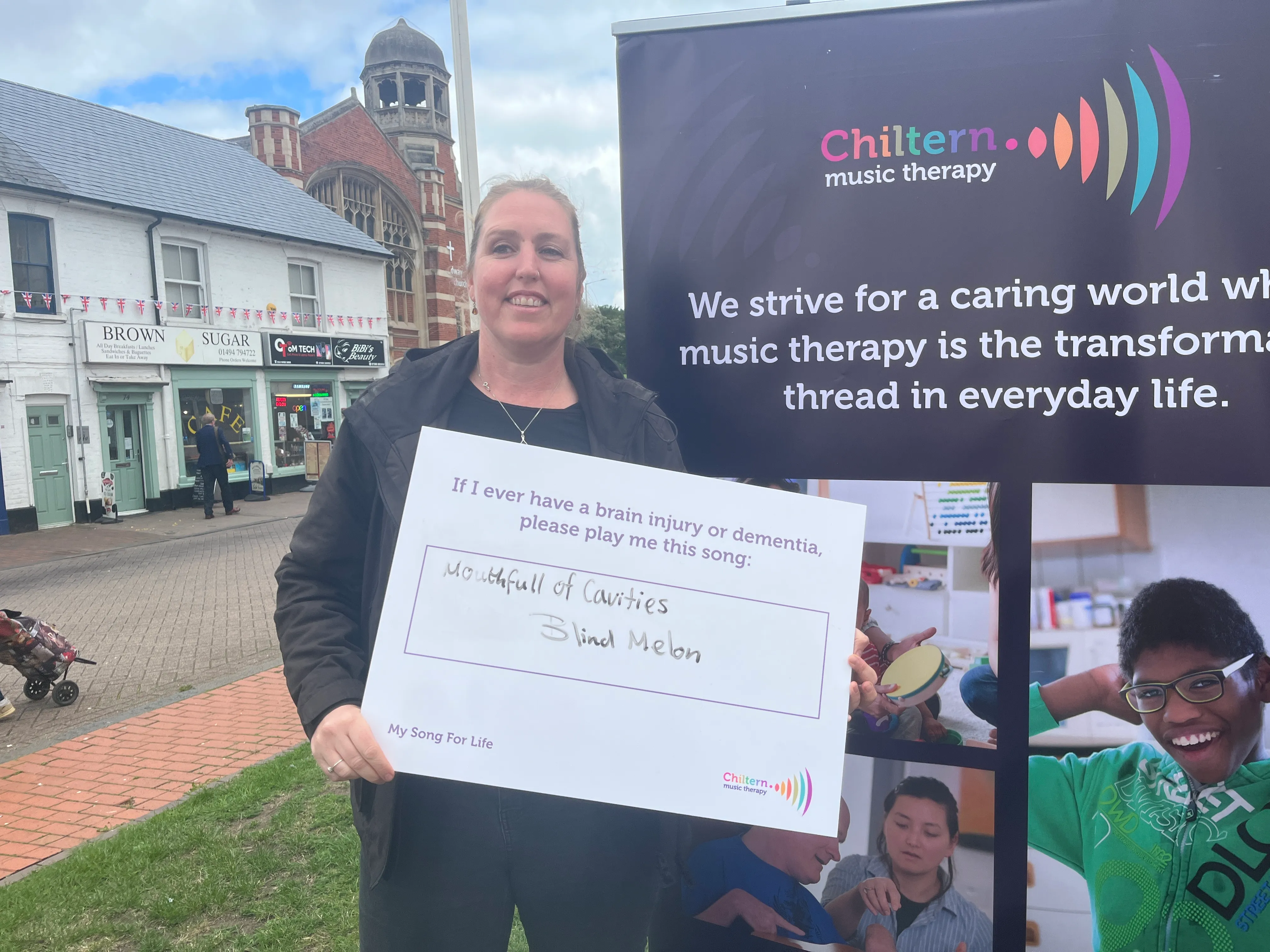 Image is of a women holding a sign that says "If I ever have a brain injury or dementia, please play me this song", underneath in handwriting it says "Mouthfull of Cavities - Blind Melon"