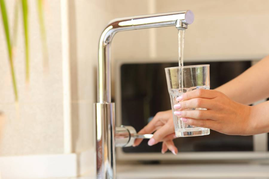 Hand filling glass with water from faucet