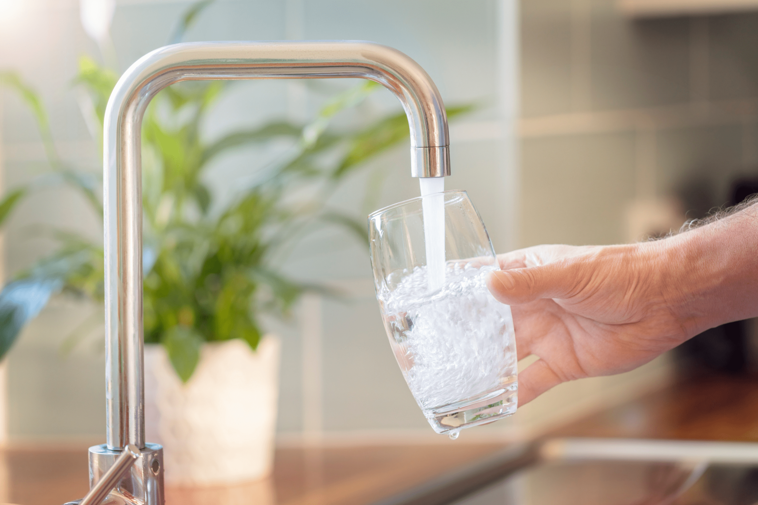 Hand filling glass with water from kitchen faucet