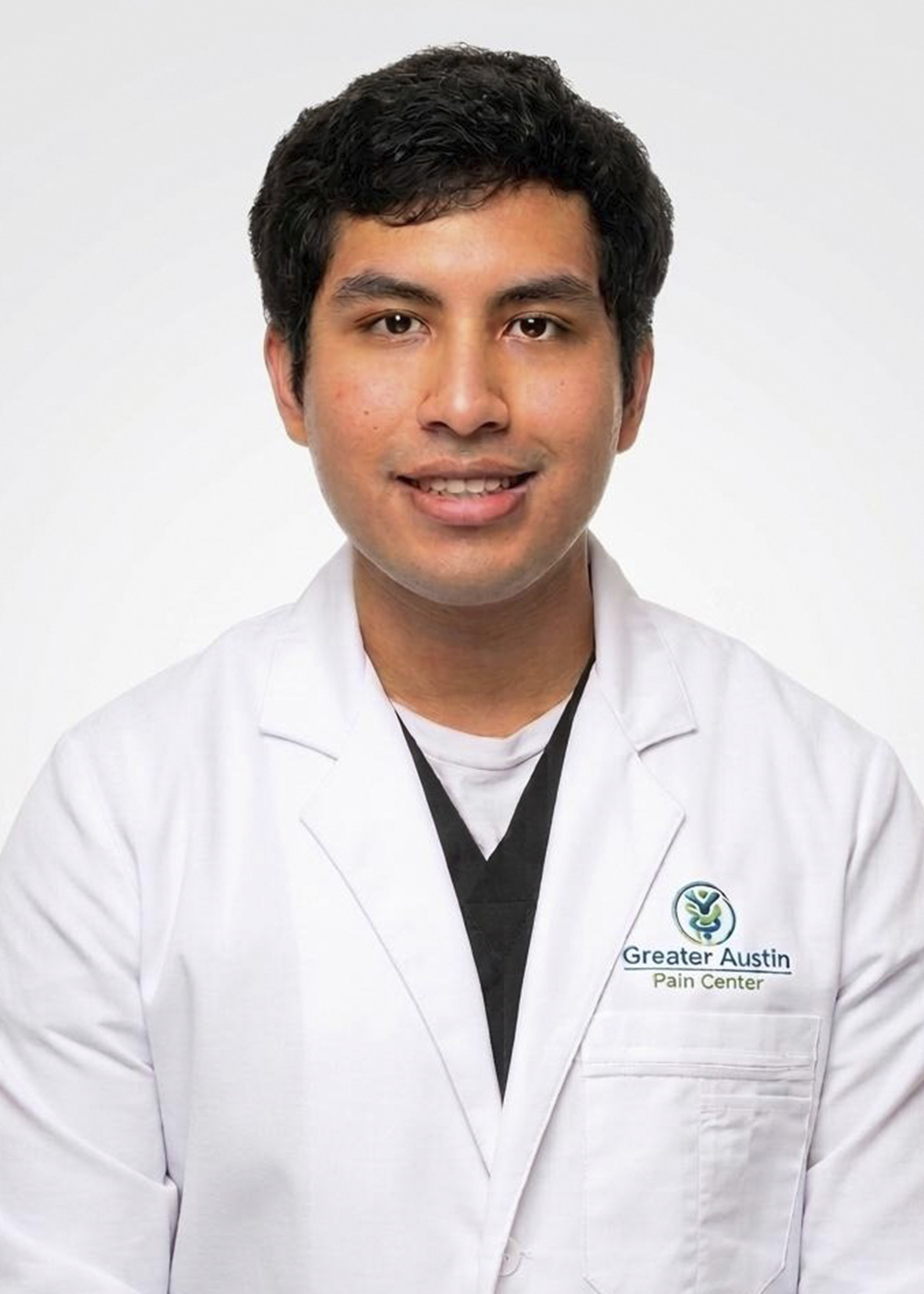 Dante Marquez, medical professional wearing a Greater Austin Pain Center white lab coat over black scrubs.