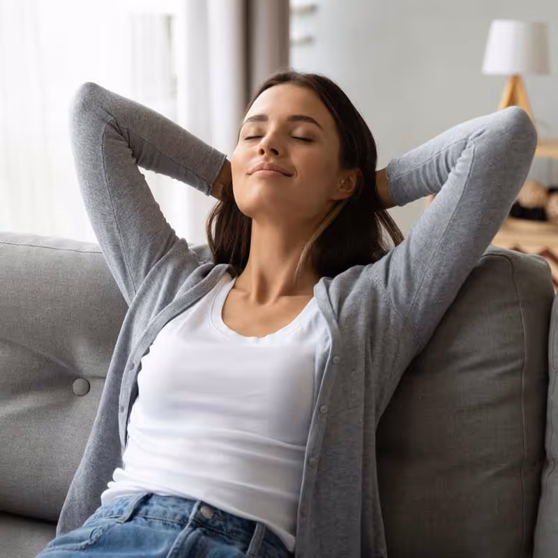 A woman sitting on a couch enjoying fresh air.