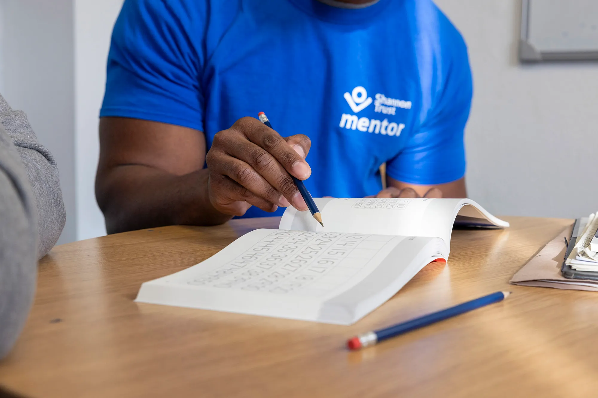 A close-up of an open Count Me In manual, with a mentor pointing to an activity on the page.