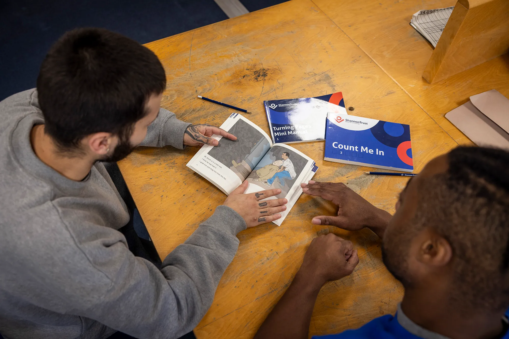 An overhead view of a table with a Write Now activity book open on it, alongside Count Me In and Turning Pages manuals.