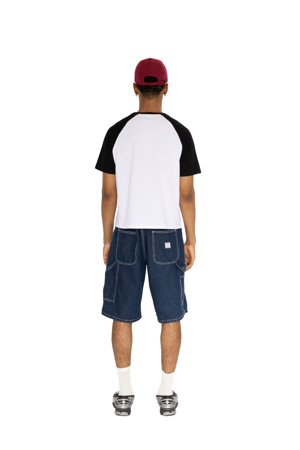 Back view of a white raglan tee with black sleeves, worn with denim shorts