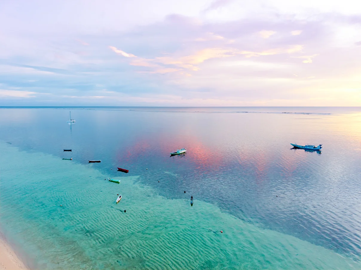Two snorkelers holding hands above coral reef with two more swimmers in clear blue water.