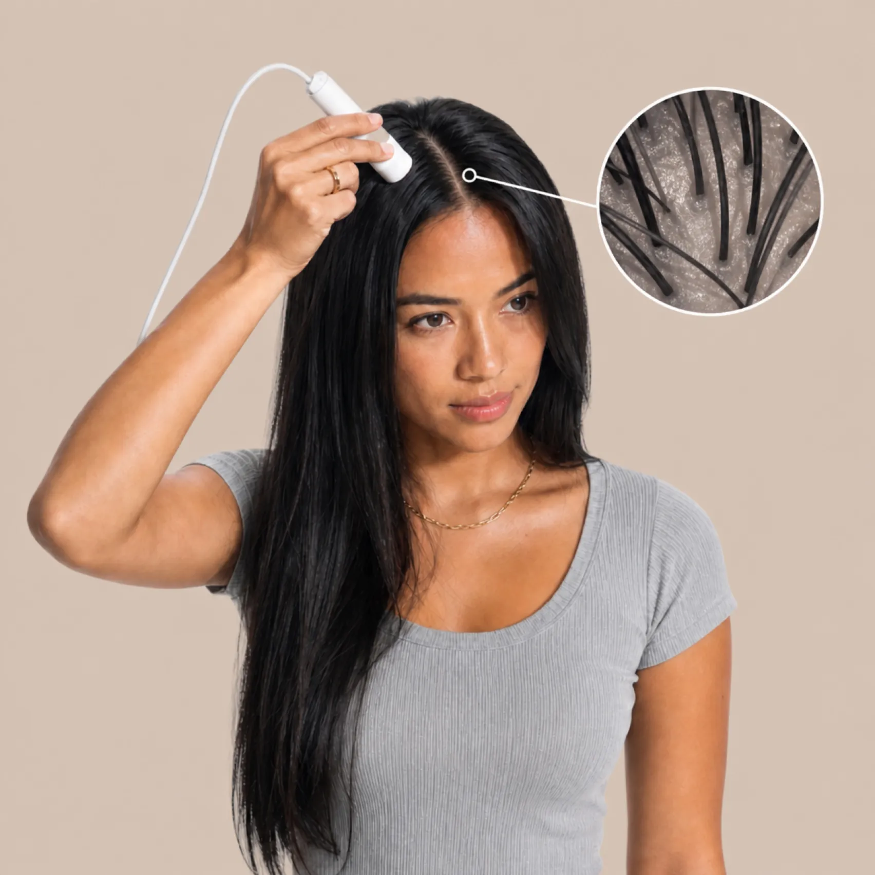 Woman with long dark hair using a handheld scalp camera device on her hair part, shown with an inset close-up view of hair follicles on the scalp.