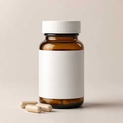 Amber glass supplement bottle with a blank white label and white screw cap beside three beige capsules on a light beige background.