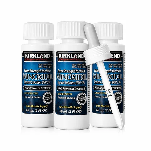 Three white bottles of Kirkland Signature Extra Strength for Men Minoxidil Topical Solution USP 5%, hair regrowth treatment, one bottle with a dropper showing clear liquid.