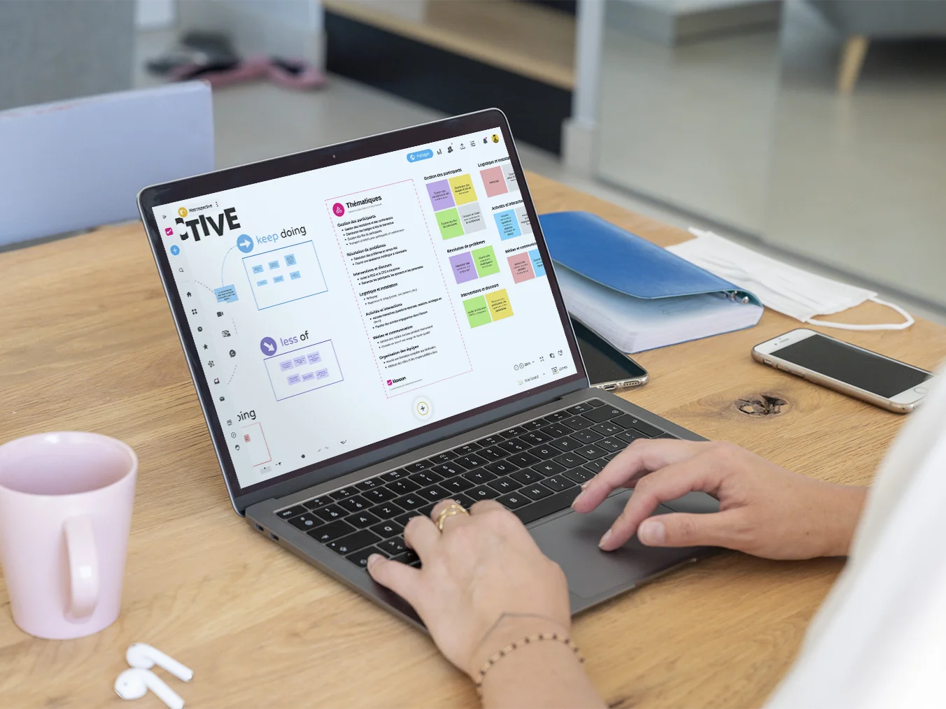 Une personne travaillant sur un ordinateur qui affiche un Board de brainstorming où les idées sont catégorisées grâce à l'IA. | Klaxoon