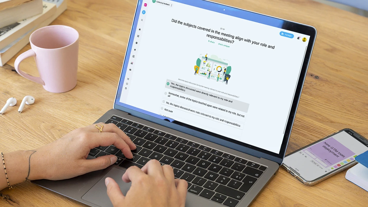 A person working on a computer displaying a “Collecting feedback” Survey. | Klaxoon