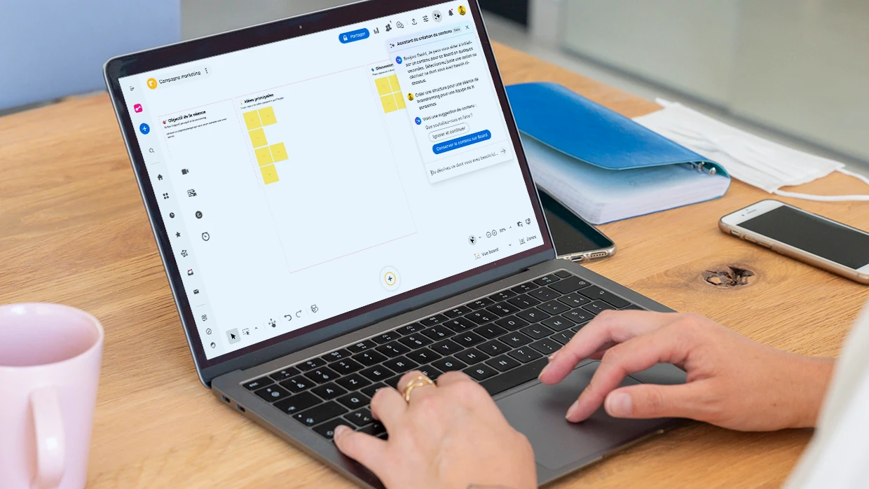 Une personne travaillant sur un ordinateur qui affiche un Board structuré pour une séance de brainstorming et un fil de discussion avec l’assistant IA. | Klaxoon