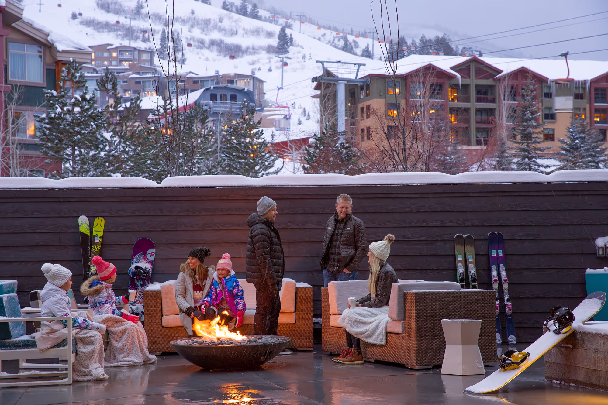 Family sitting by the firepit with snow slopes in the background