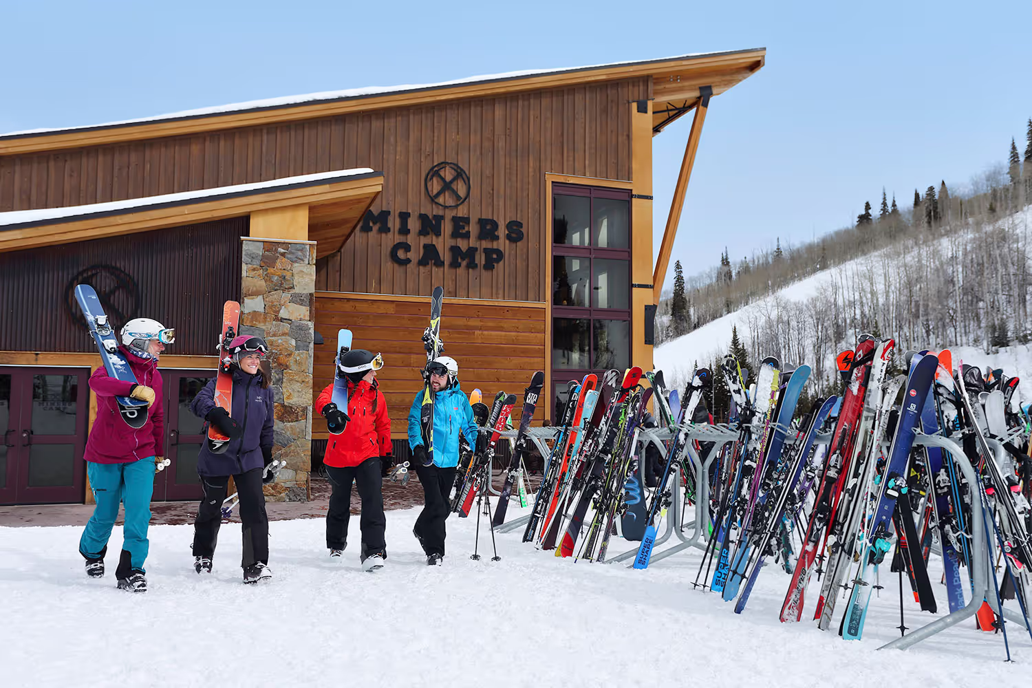 four people walking and holding their skis