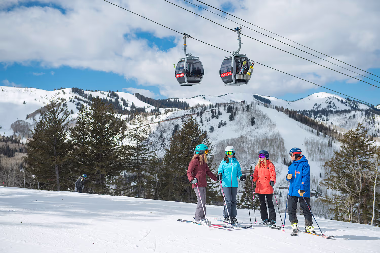 four skiers standing under ski lift