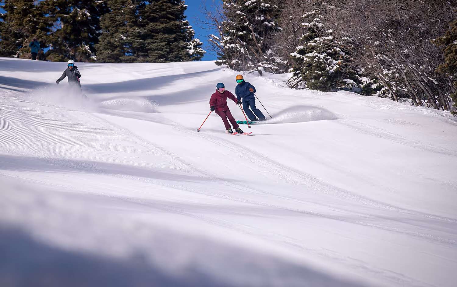three skiers coming down the mountain