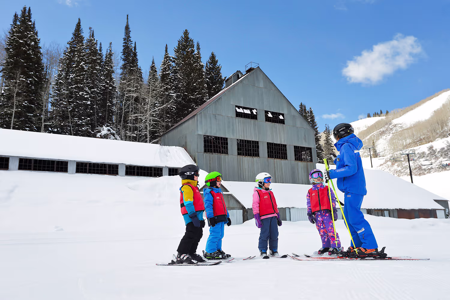 instructor teaching four children to ski