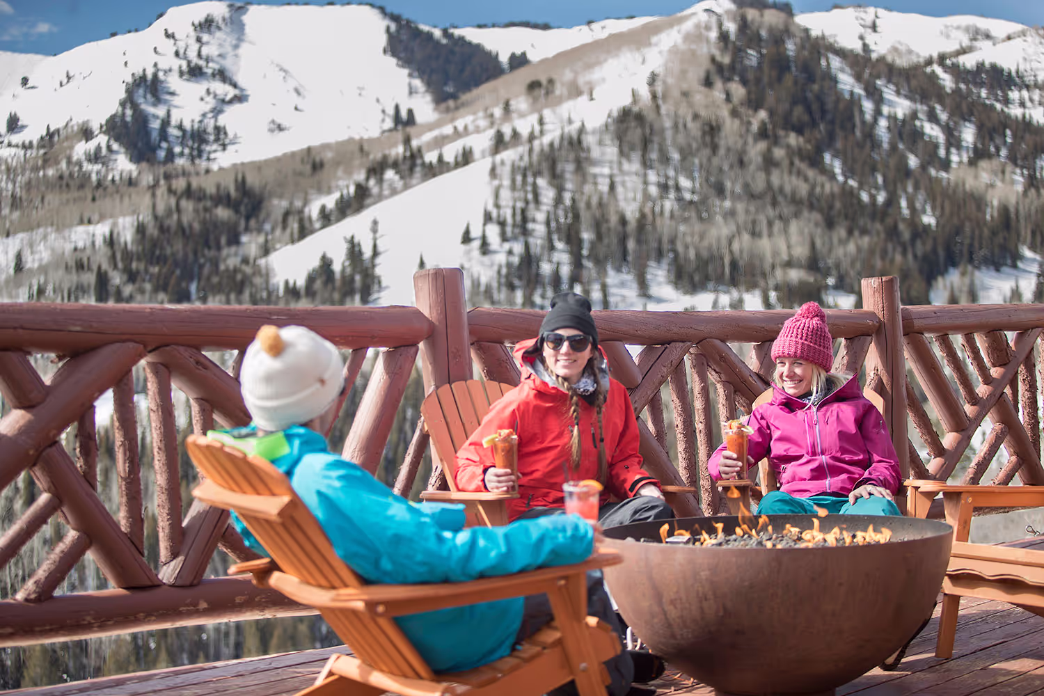 three people having cocktails by the fire