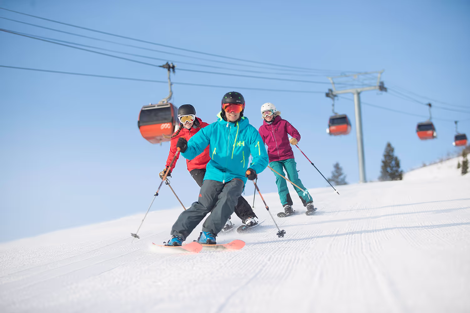 three skiers coming down the mountain