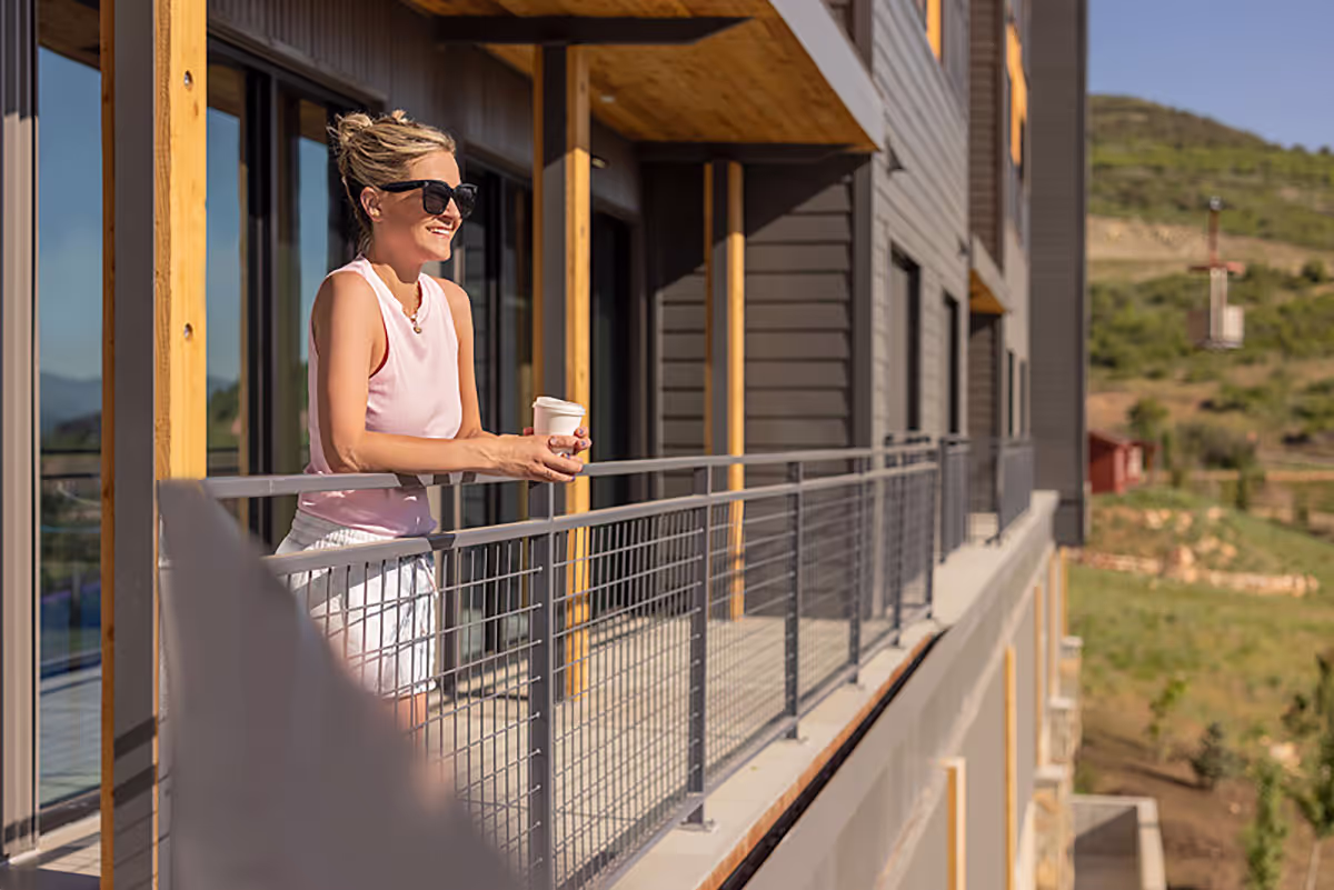Woman standing on balcony with a cup of coffee.