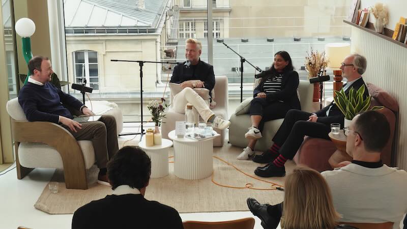 Several people being filming whilst chatting on a podcast and with a live audience.
