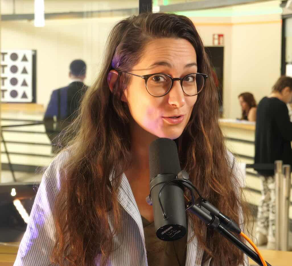 Woman looking at the camera talking into a microphone.