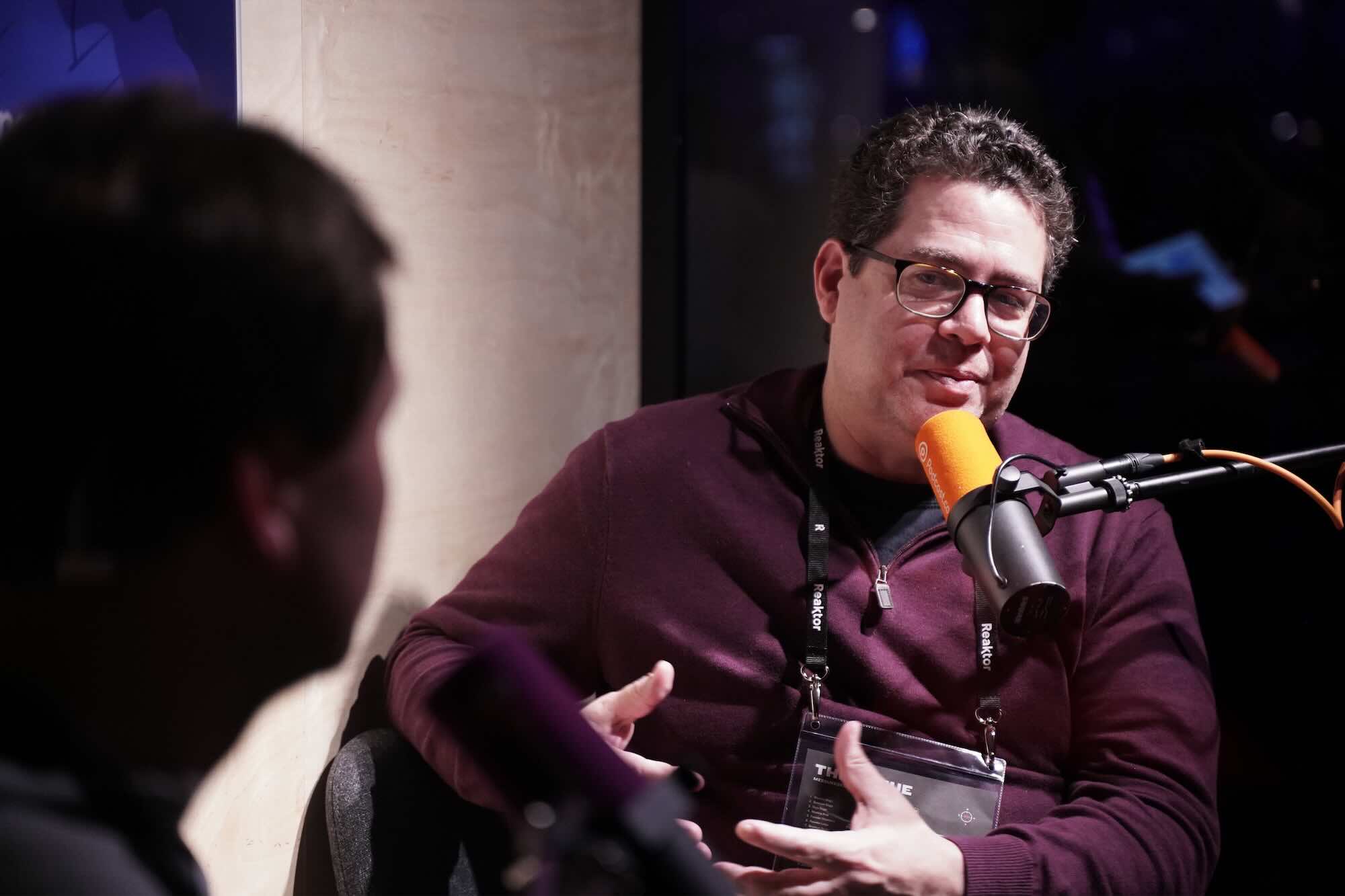 Two men chatting into microphones for a podcast at an event.