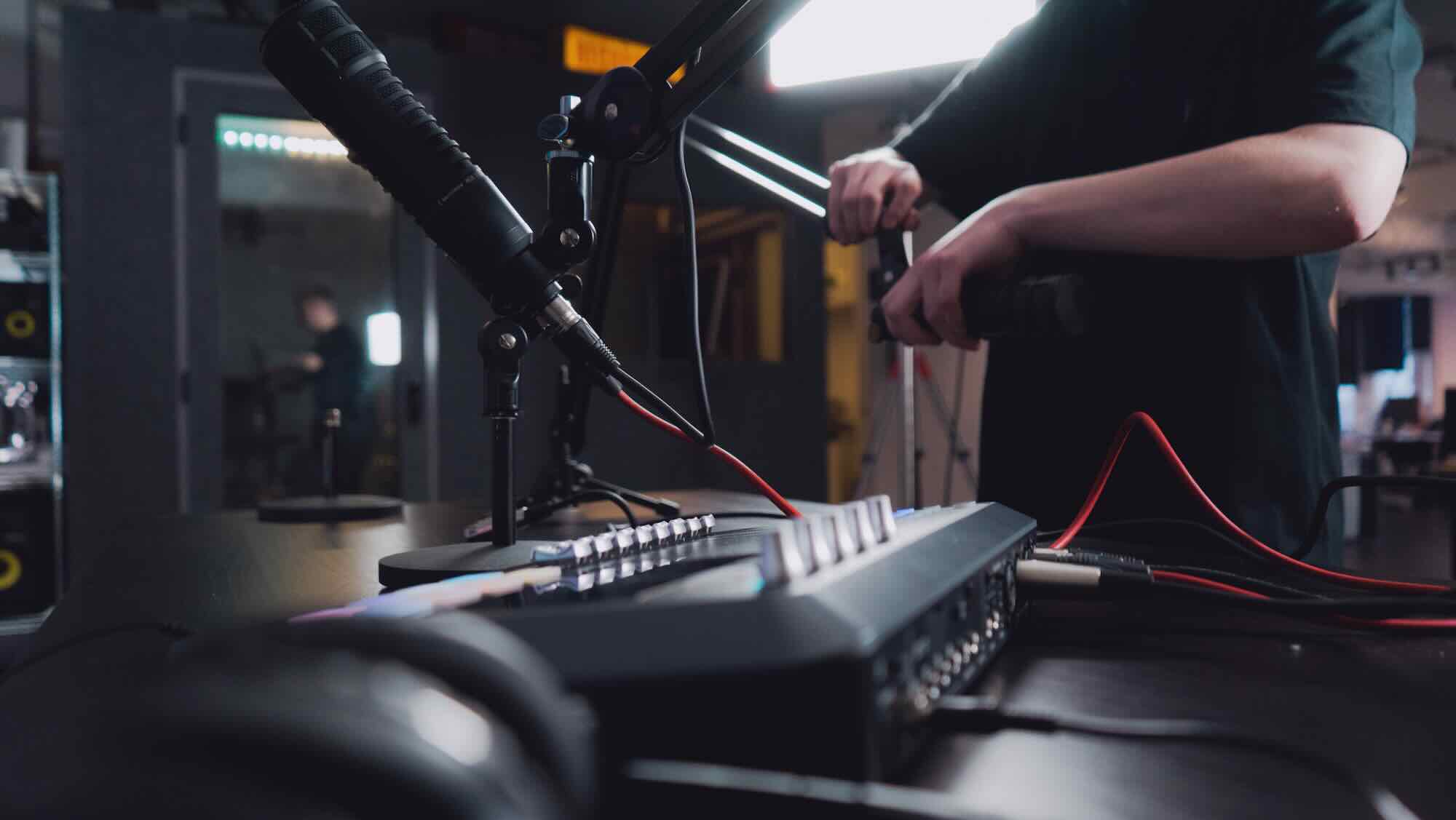 Audio equipment being setup, like a mixer and microphone, on a table.