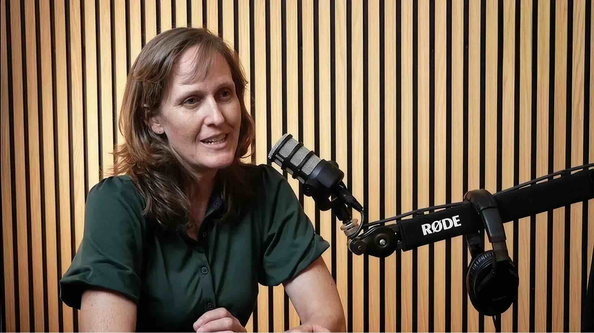 Woman talking into microphone with a sound proof background.
