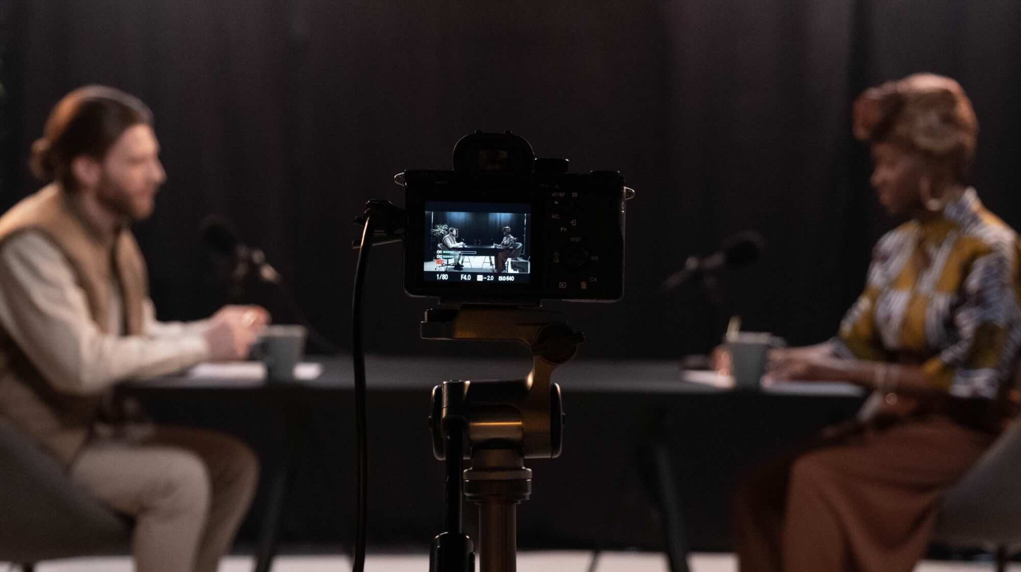Two people chatting for a podcast whilst being filmed.