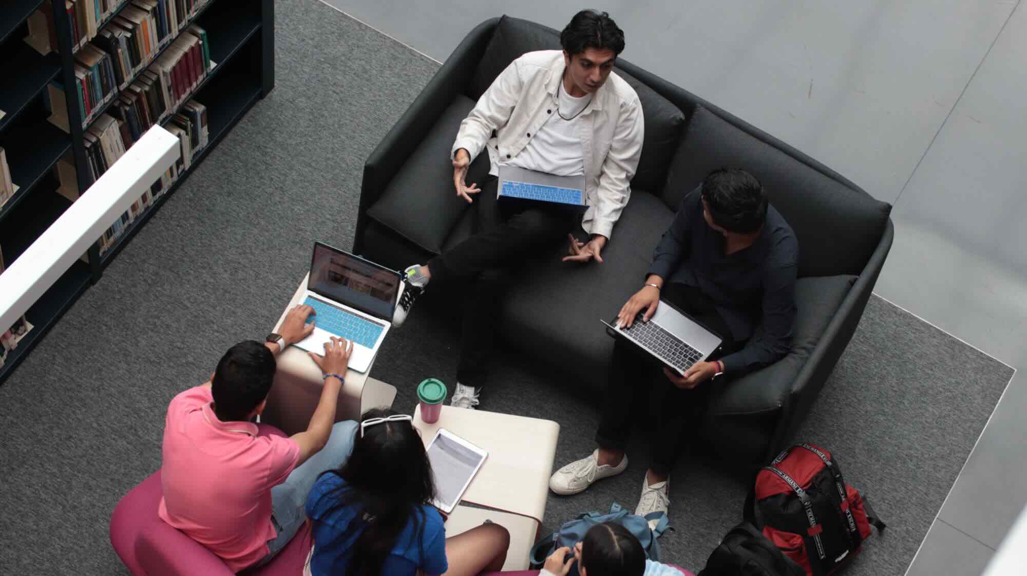 Students sat around chatting with laptops and books open.