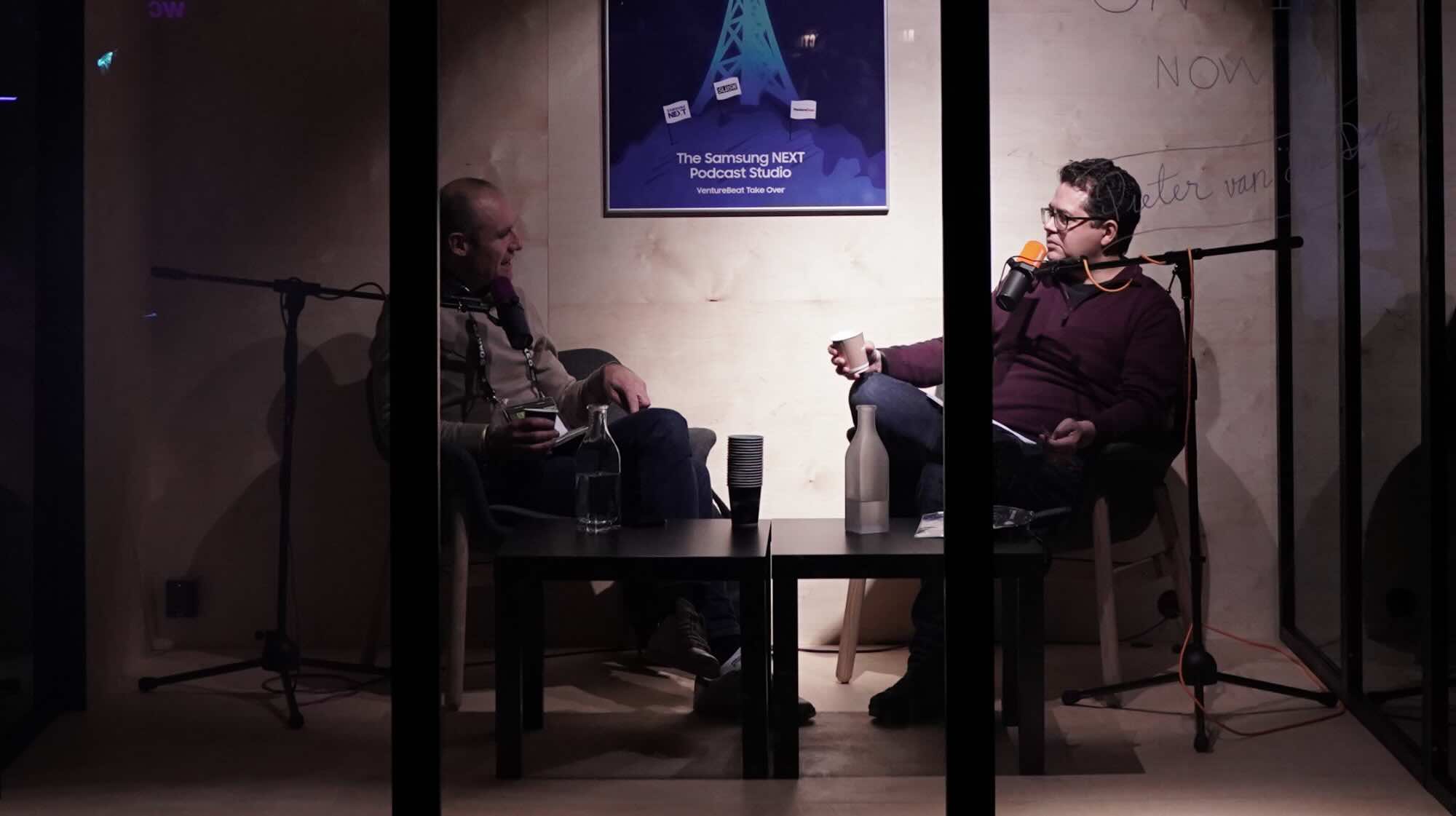 Two people chatting on a podcast in a sound booth at an event.