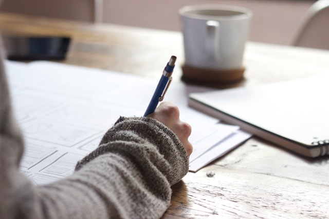 Person sitting at a table writing a letter