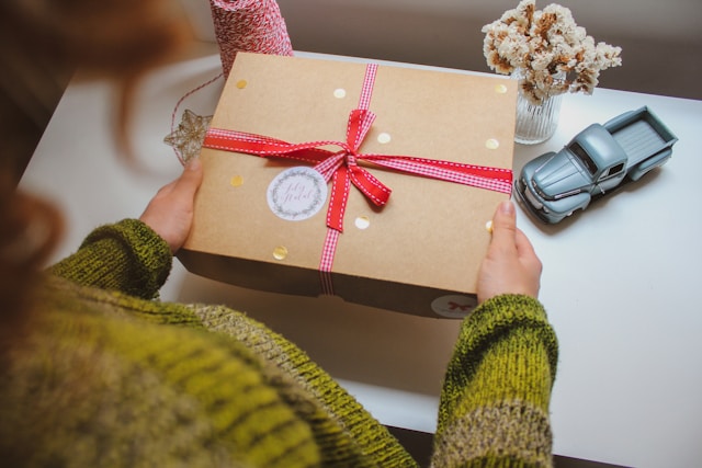 person holding a gift box wrapped with a red bow