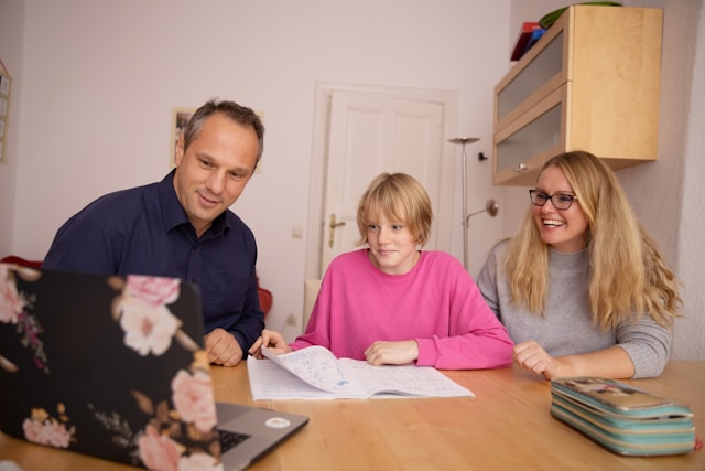 Host family and exchange student sitting at a table with a laptop