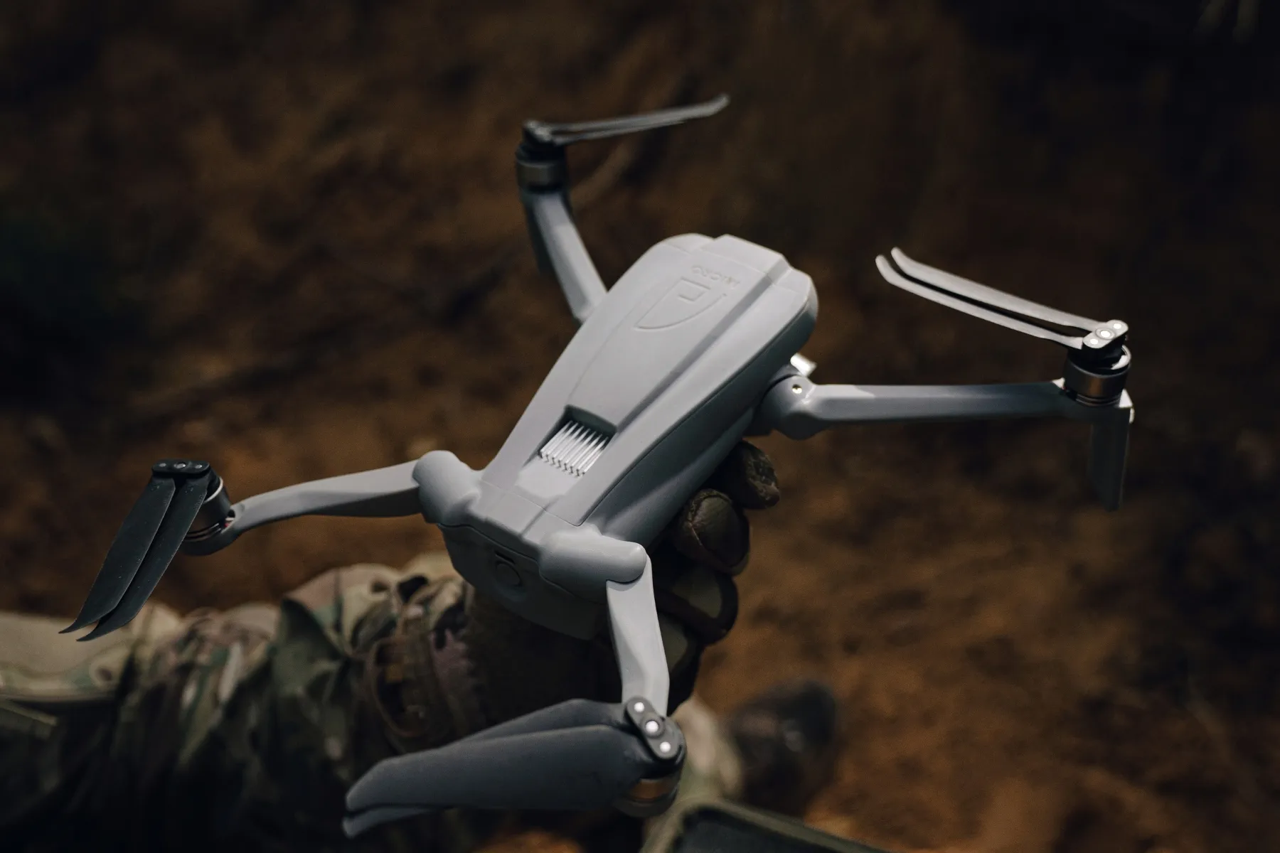 Operator holding AtlasMICRO in a gloved hand in the forest