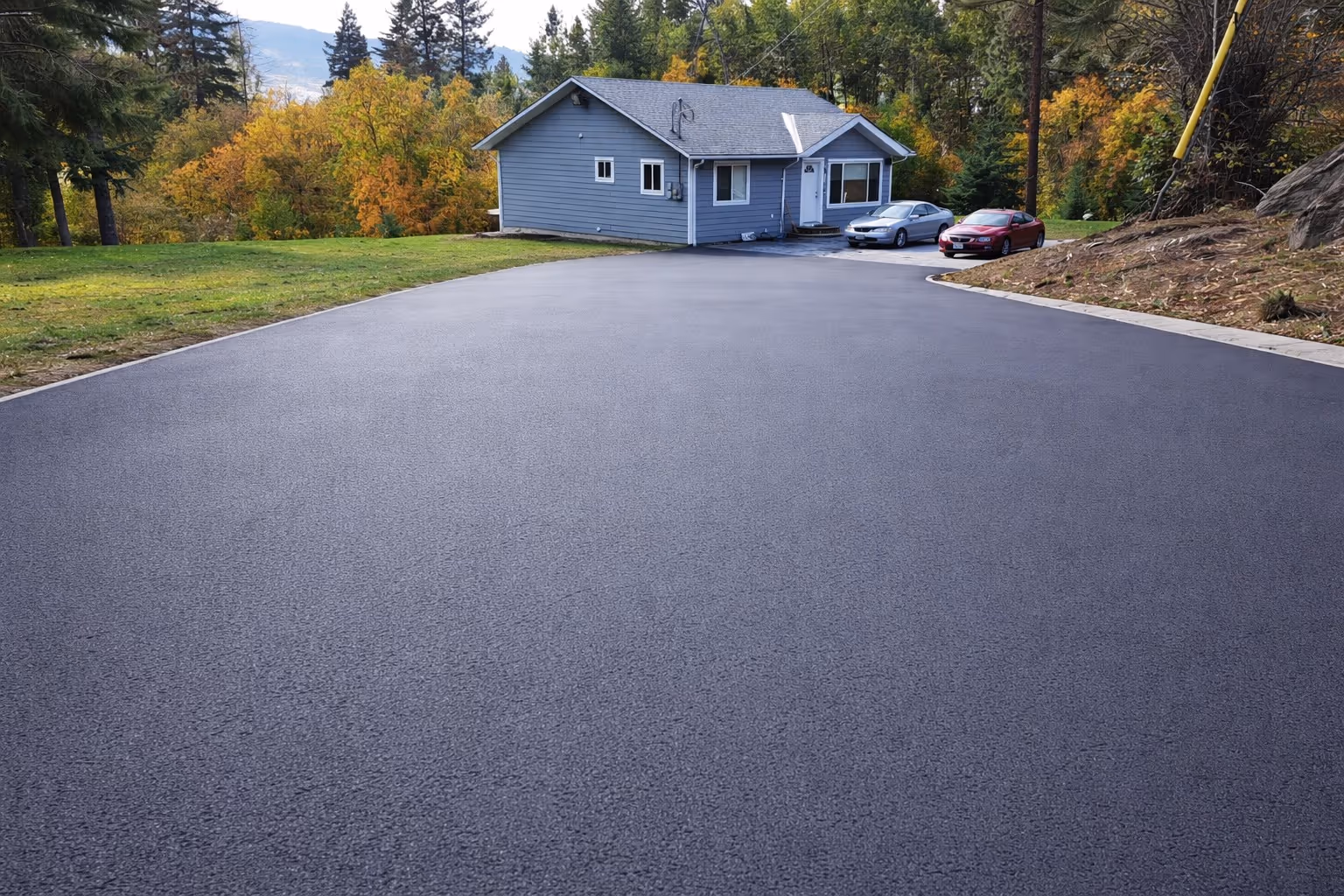 Smooth black asphalt driveway sloping toward the road at a Vernon, BC property