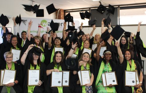Group of students celebrating their graduation, throwing their mortarboards in the air and holding their certificates