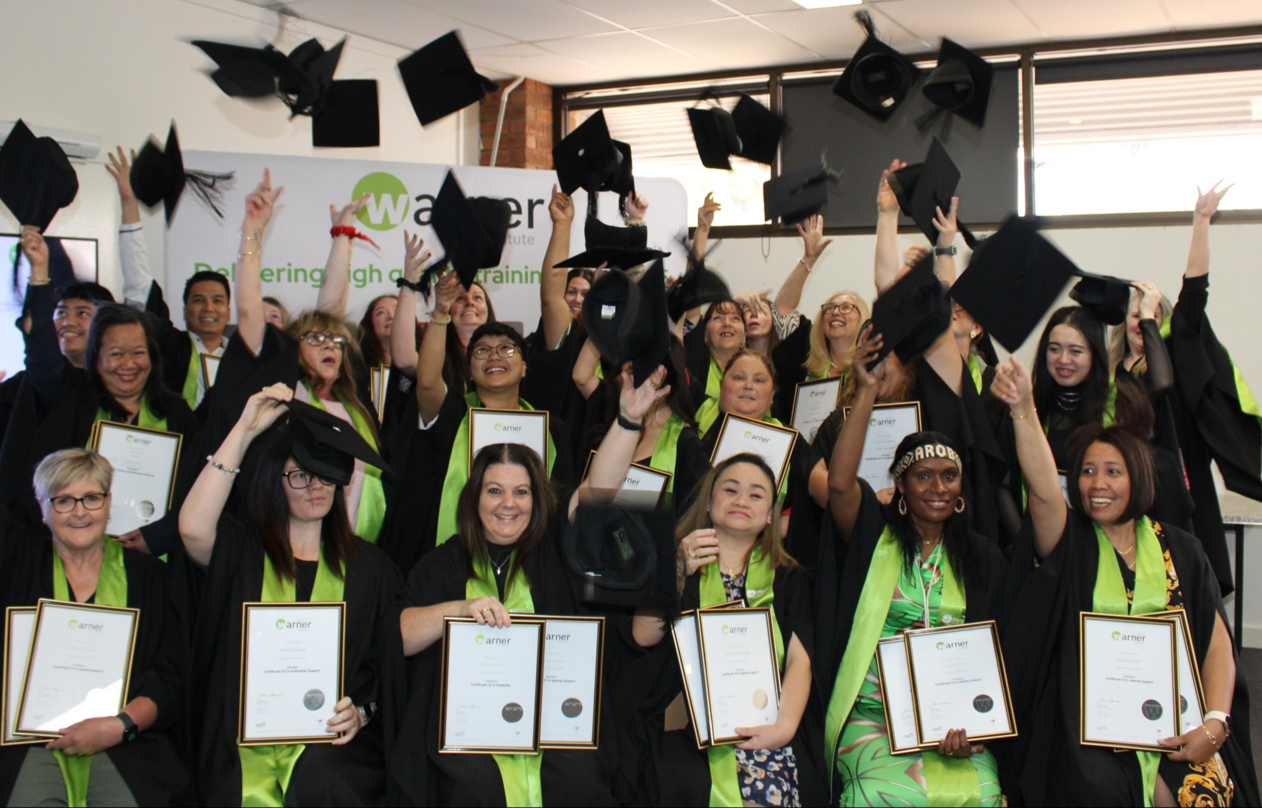 Group of students celebrating their graduation, throwing their mortarboards in the air and holding their certificates