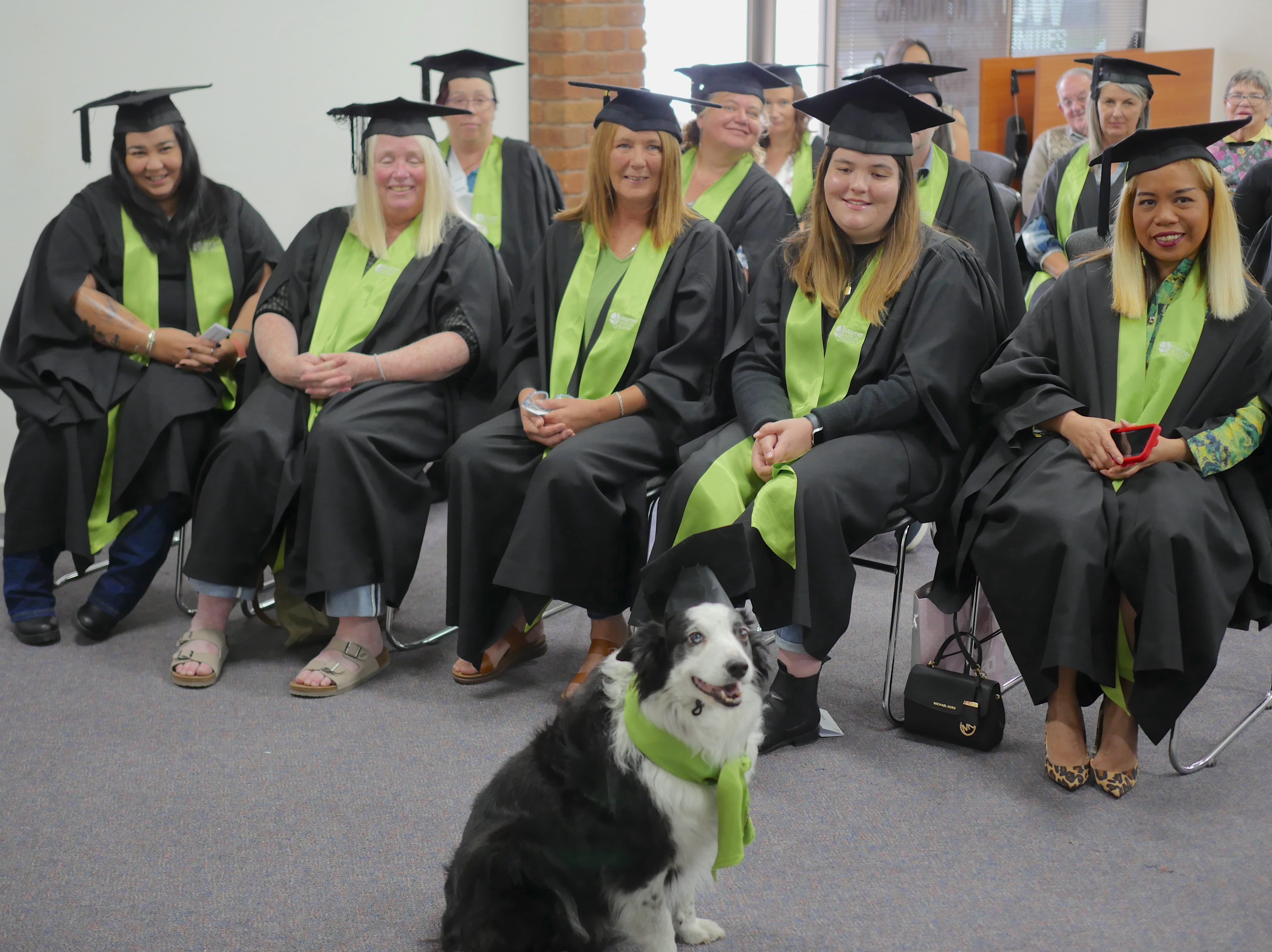 Group of students celebrating their graduation, throwing their mortarboards in the air and holding their certificates