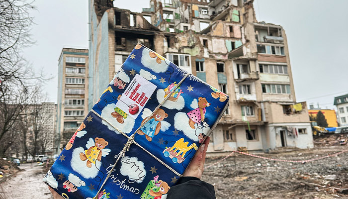 Weihnachtspäckli vor einem zerbombten Haus in der Ukraine als Zeichen der Hoffnung und Anteilnahme für getötete Kinder
