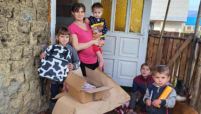 Mutter mit vier Kindern aus Poroschkowo, Ukraine, steht vor ihrem Haus mit Weihnachtspäckli.
