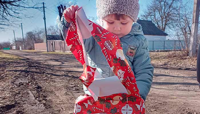Kleinkind aus Dnipro, Ukraine, packt sein Weihnachtspäckli aus.