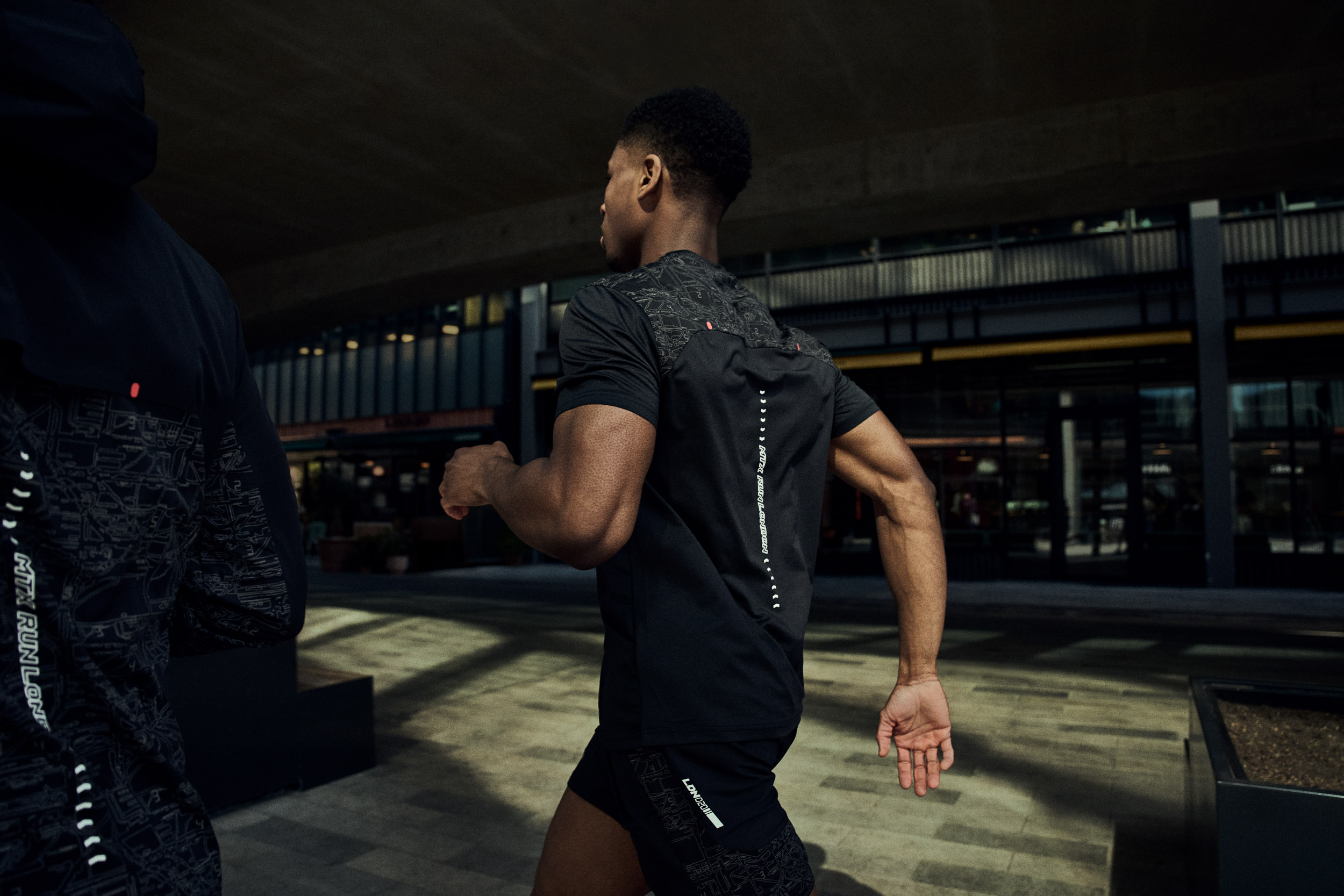 Back view of a runner showing Montirex running top detail in shadowed urban light.
