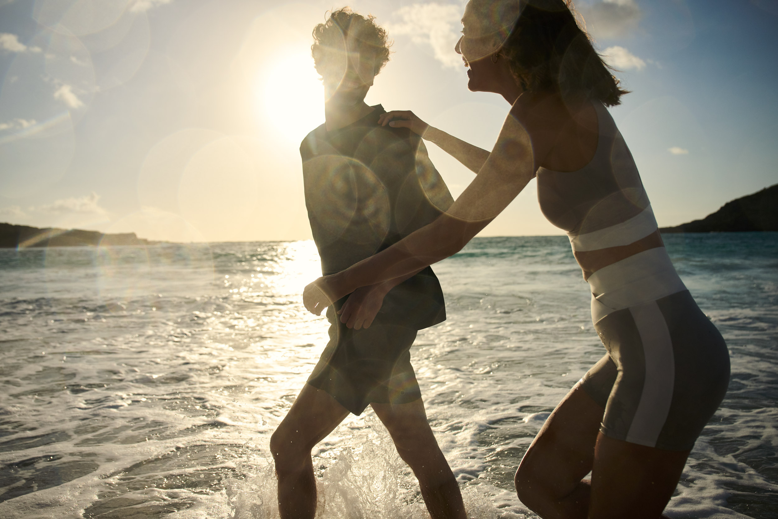 Couple playing in shallow water at sunset on the beach