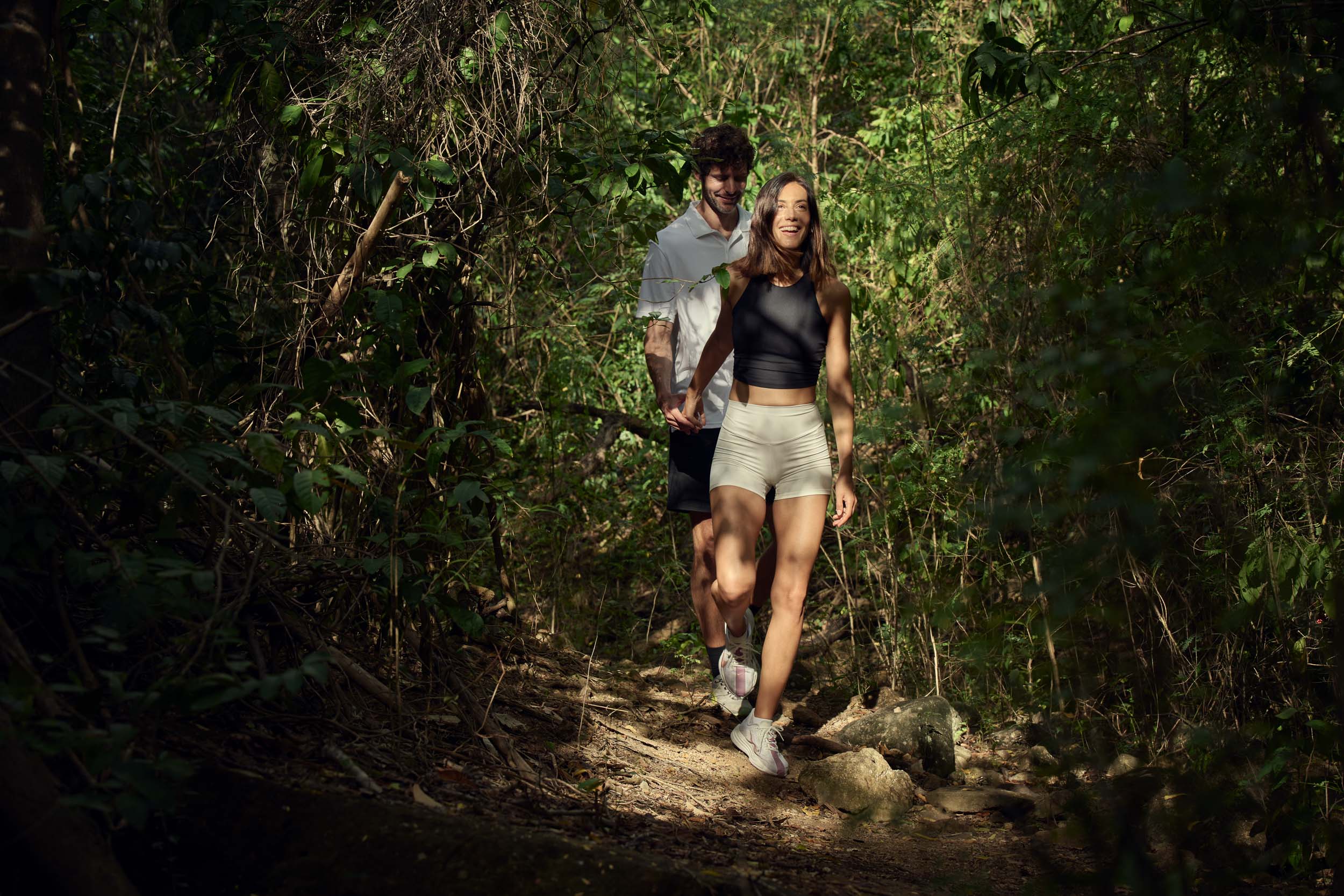 Couple walking together along a shaded forest path in the jungle