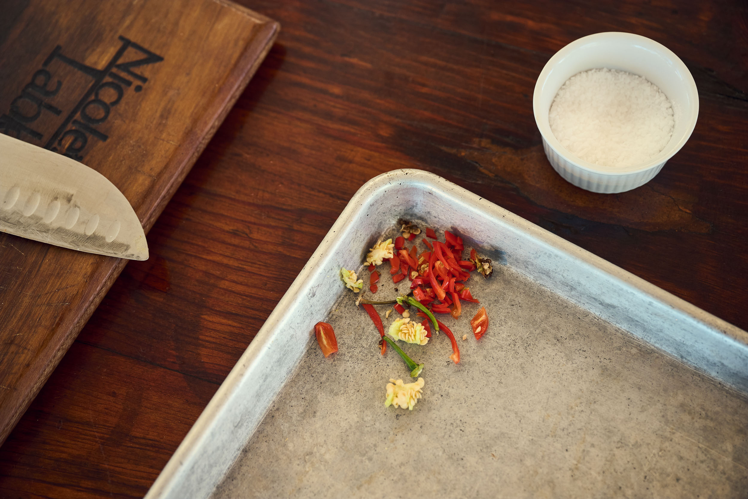 Chopped peppers, salt and kitchen tools on a wooden table