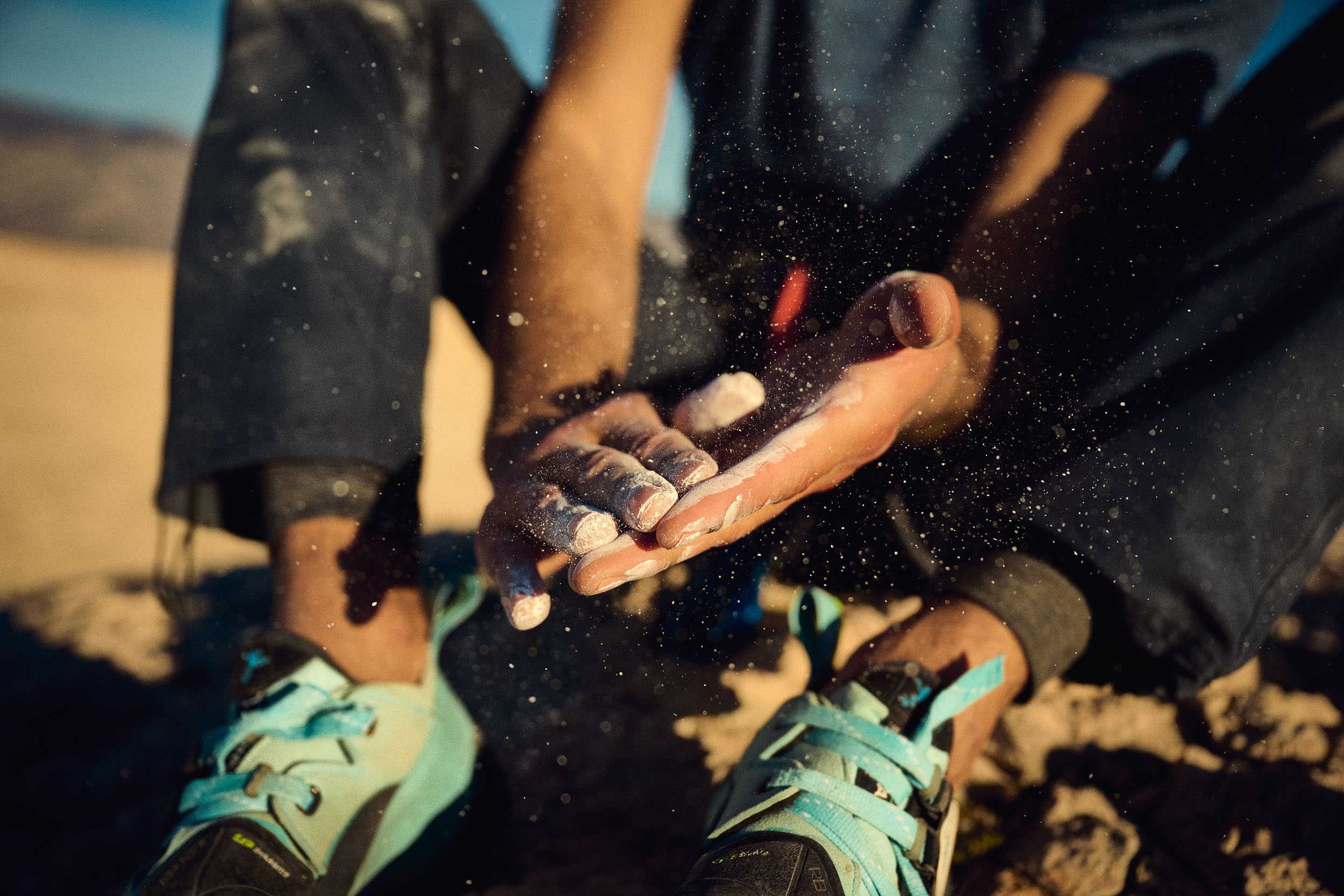 Chalk dust rising from a climber’s hands before climbing.