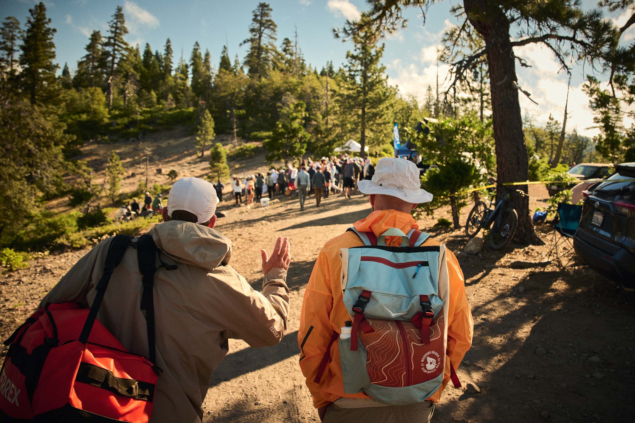 Two crew members walk towards a mountain aid station carrying race equipment.