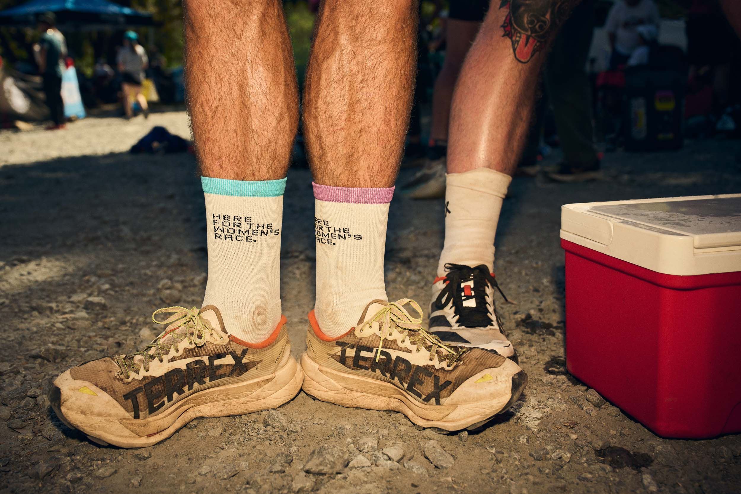 ‘Here for the women’s race’ socks above mud-covered Adidas TERREX trail shoes.